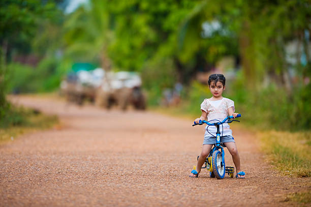 A cute little Asian girl is having fun riding a tricycle on holiday,An Asian Girl (Chinese) plays in the wild