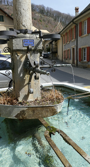 Old water fountain in plaza of village of Romainmôtier Switzerland