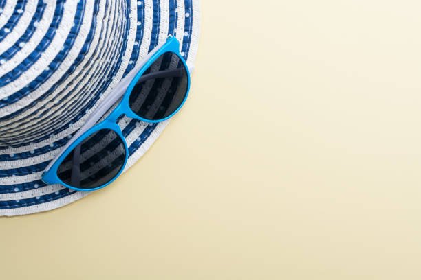 istock Top view of a hat and blue sunglasses on a beige surface 952487452