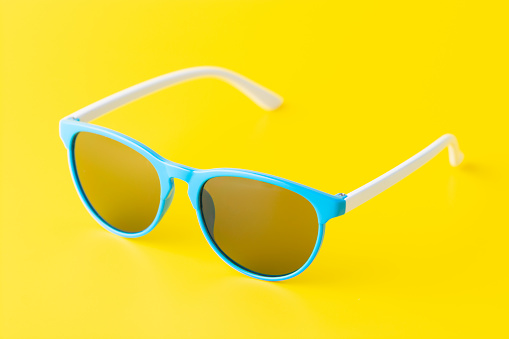 A minimalist arrangement of blue sunglasses on a bright yellow background