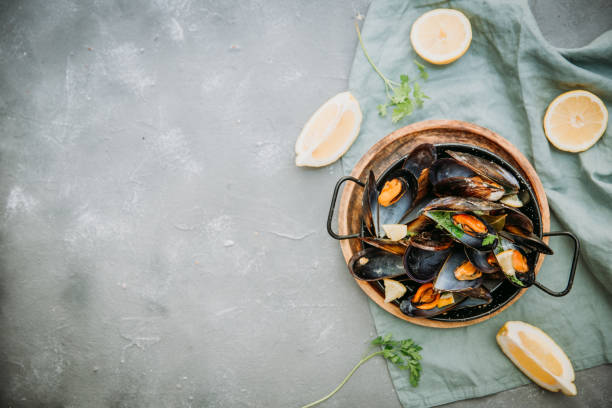 istock Traditional blue mussel in white wine on stone background, top vie, copy space 952490902