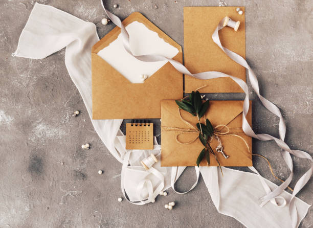 Mockup wedding invitation flat lay. Craft paper with olive brunch on stone background