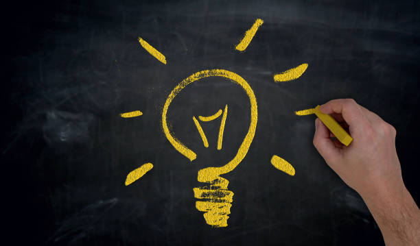 istock Hand paints with chalk lightbulb on blackboard concept 952514396