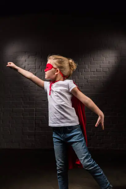 female child flying in red superhero mask and flying