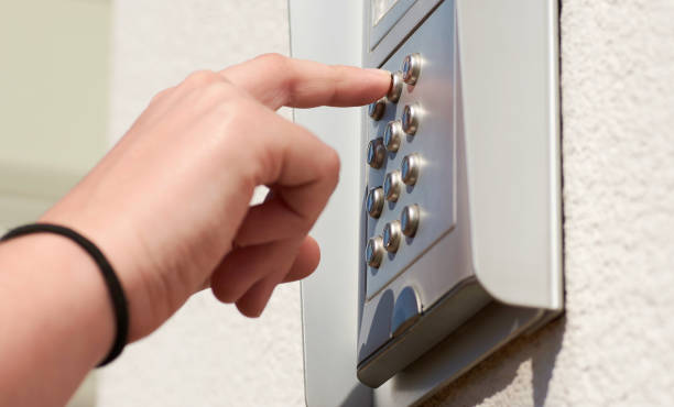 istock Door numeric encoding device on the building, with female hand holding buttons 952532150