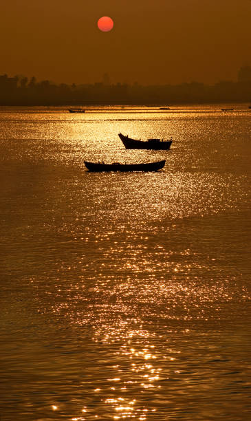 Sunrise over South Mumbai Sunrise over South Mumbai as seen across glittering Arabian Sea with silhouetted fishing boats in foreground maharashtra stock pictures, royalty-free photos & images