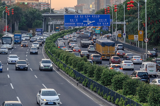 China, Shenzhen, 2018-03-09: Evening traffic in big city, cars on divided highway road, traffic jam at street, busy urban view at sunset. Air pollution in town, benzopyrene, CO2. Photo with blur in motion