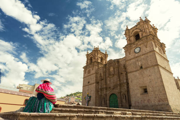 Woman with keperina (bag on her back) sitting on the steps of the Cathedral of Puno (Peru) stock photo
