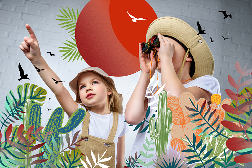children in safari costumes and hats pointing and looking in binoculars