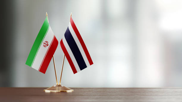 istock Iranian And Thai Flag Pair On A Desk Over Defocused Background 952595172