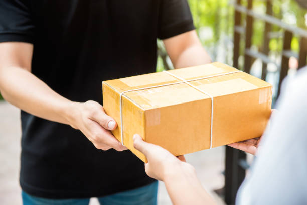 istock Delivery man in black uniform delivering package to recipient 952625312