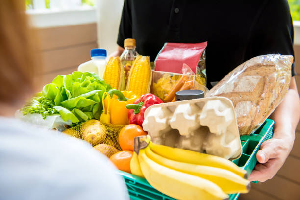 lieferbote liefern lebensmittel an kunden zu hause - food bread groceries basket stock-fotos und bilder