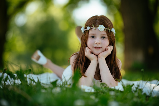 Beautiful red hair girl laying on grass. Shallow DOF. Developed from RAW; retouched with special care and attention; Small amount of grain added for best final impression. 16 bit Adobe RGB color profile.