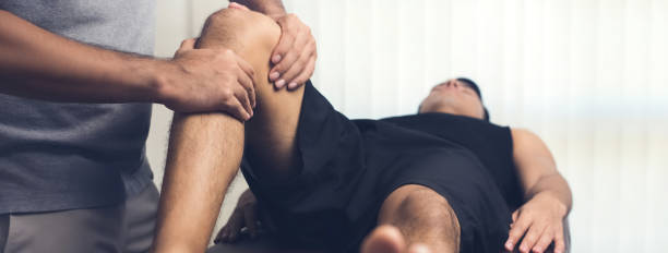 Therapist treating injured knee of athlete male patient Therapist treating injured knee of athlete male patient - sport physical therapy concept, panoramic banner man massage stock pictures, royalty-free photos & images