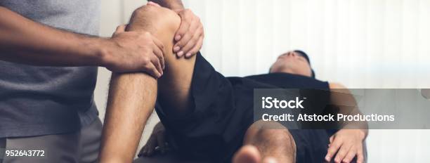 Therapist Treating Injured Knee Of Athlete Male Patient Stock Photo - Download Image Now