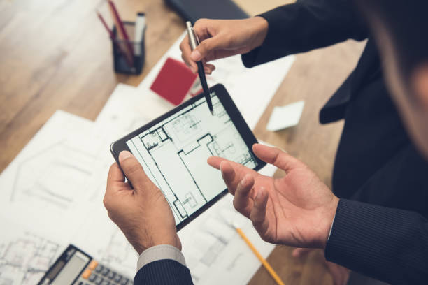 agente de bienes raíces con arquitecto o cliente equipo de comprobación de un modelo de vivienda y sus planos digitalmente con una tableta - examining built structure house industrial fotografías e imágenes de stock