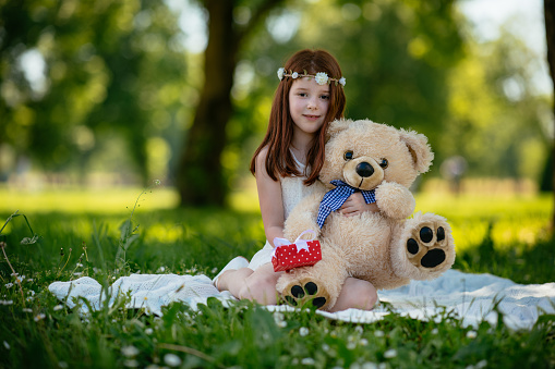 Young girl happily hugging a huge teddy bear. Shallow DOF. Developed from RAW; retouched with special care and attention; Small amount of grain added for best final impression. 16 bit Adobe RGB color profile.
