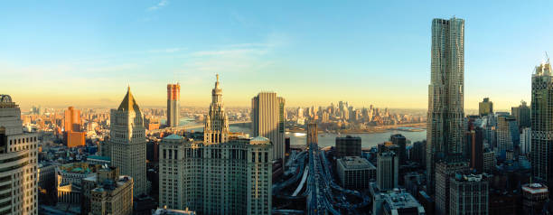 The panoramic scenic view to the Manhattan Downtown, over the Brooklyn Bridge and East River toward Brooklyn. The skyline includes the major buildings: Manhattan Municipal Building, New York by Gehry, Thurgood Marshall United Square Courthouse, One Brooklyn Bridge Plaza, and more. Aerial drone shot. la panorámica escénica a la manhattan downtown, sobre el puente de brooklyn y el río east hacia brooklyn. el horizonte incluye los principales edificios: edificio municipal de manhattan, nueva york por gehry, thurgood marshall unidos plaza del palacio de justicia, un brookl