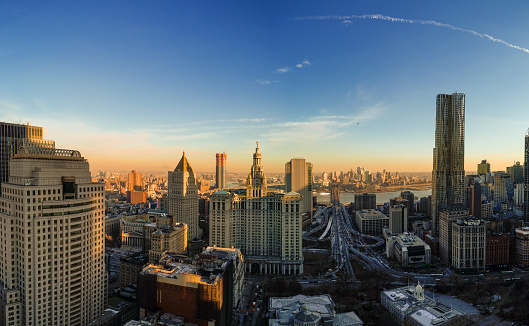 The panoramic scenic view to the Manhattan Downtown, over the Brooklyn Bridge and East River toward Brooklyn. The skyline includes the major buildings: Manhattan Municipal Building, New York by Gehry, Thurgood Marshall United Square Courthouse, One Brooklyn Bridge Plaza, and more. Aerial drone shot.