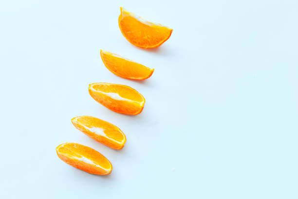 Line of fresh orange slices lie in line on white table, copy space