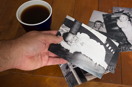 A man with a pile of old photo's from his childhood looking through them.