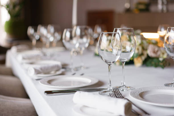 istock Table setting in the restaurant, glasses in the foreground. Luxury wedding reception. Flower arrangement on table in restaurant. Stylish decor and adorning. 952701458