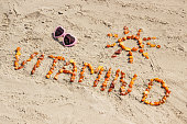 Sunglasses, inscription vitamin D and shape of sun on sand at beach, summer time and healthy lifestyle concept