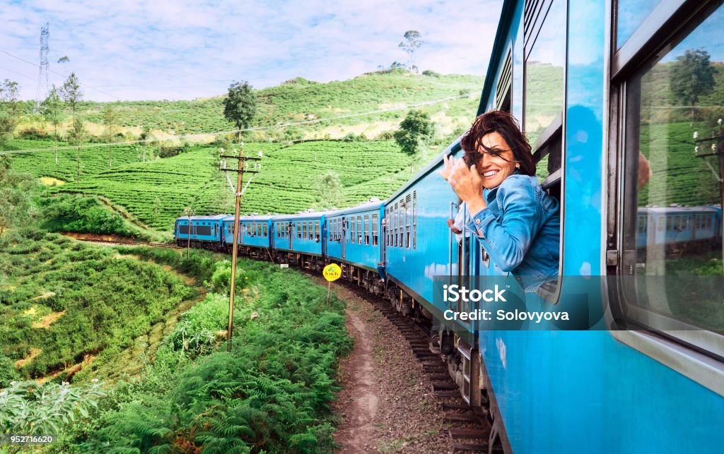 Happy smiling woman looks out from window traveling by train on most picturesque train road in Sri Lanka Travel Stock Photo