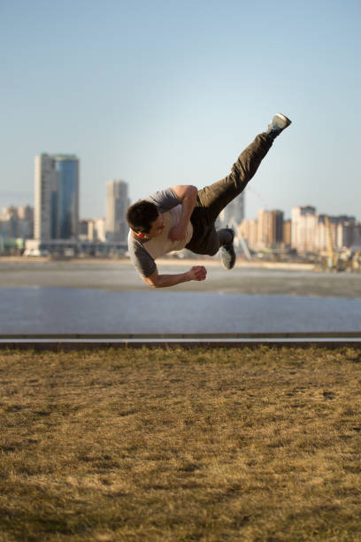 istock Young man fighter performs acrobatic kick in front of skyline 952723514