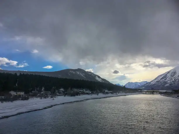 Dark clouds and blue sky appear over the White Pass & Yukon Railway bridge in town of Carcross, Yukon Territory, Canada.