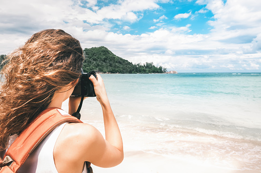 Young girl photographer with backpack taking photo beautiful seascape, Thailand, Koh Phangan