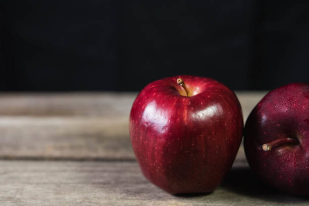 istock red apple on wood table on dark background 952735030