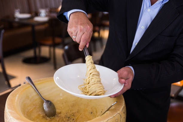istock Chef neatly plating spaghetti carbonara in cheese wheel on white plate. 952742378