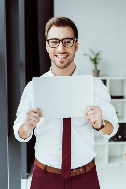 istock handsome smiling businessman holding laptop in modern office 952745318