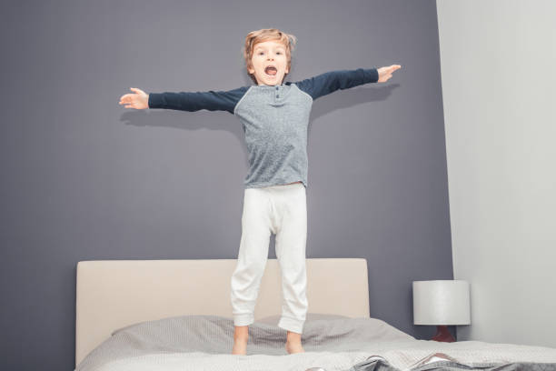 istock Playful boy with arms outstretched having fun in bedroom. 952762280
