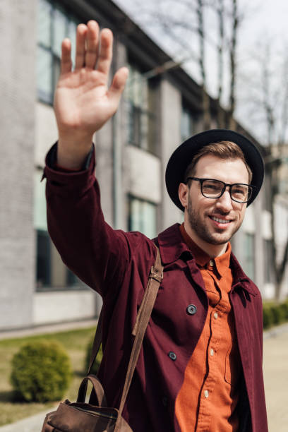 istock handsome young man with bag waving to someone 952762428