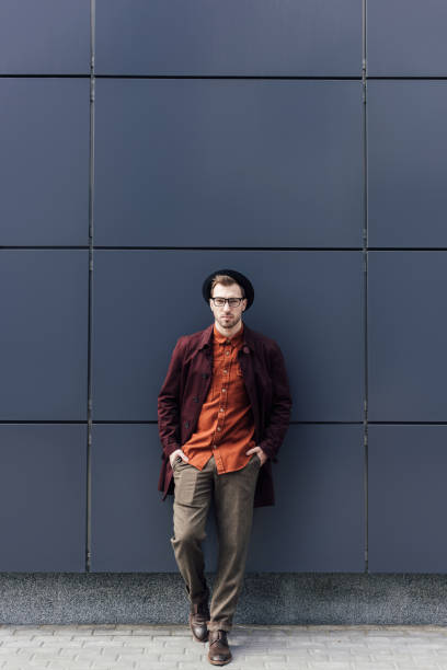 istock handsome stylish man in hat standing at black wall 952767876