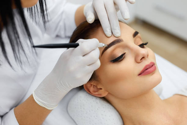 istock Beautician Doing Eyebrow Makeup Tattoo On Woman Using Machine 952772608