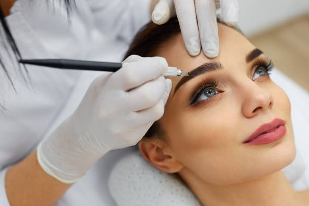 istock Beautician Doing Eyebrow Makeup Tattoo On Woman Using Machine 952772632