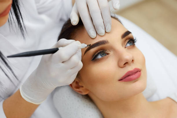 istock Beautician Doing Eyebrow Makeup Tattoo On Woman Using Machine 952772648