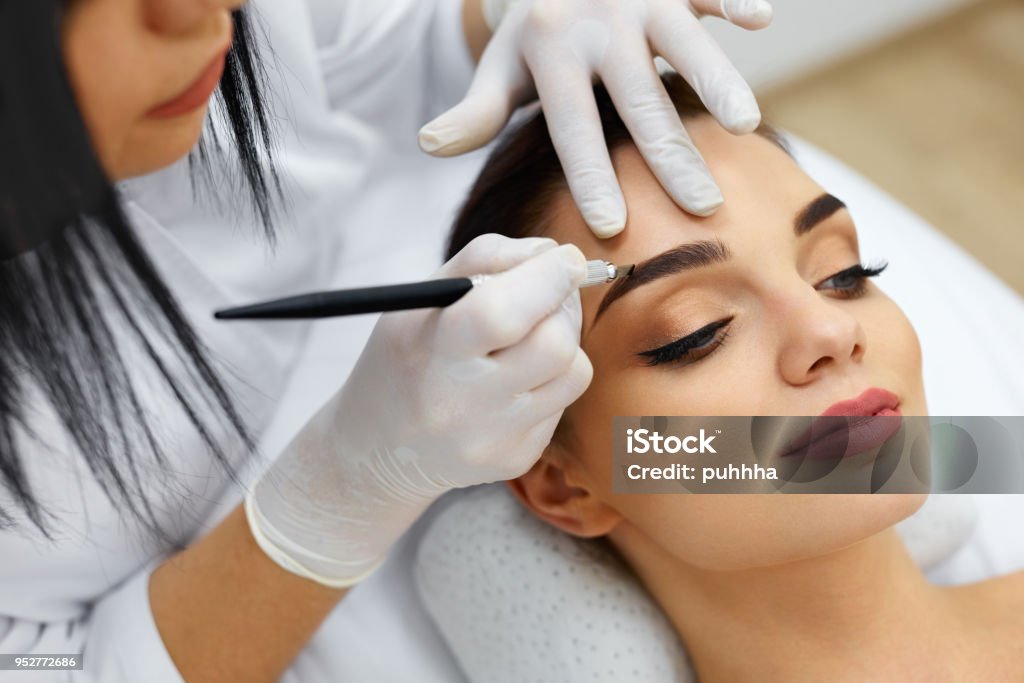 Beautician Doing Eyebrow Makeup Tattoo On Woman Using Machine Stock Photo -  Download Image Now - iStock