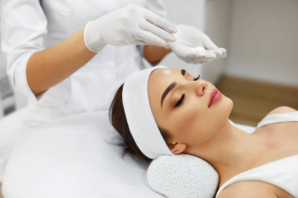 Girl At Spa Salon. Beautician Applying White Cosmetic Powder Spa Salon. Beautician Does Cosmetic Procedures Applying White Cosmetic Powder On Woman Face. Closeup Of Beautiful Female Receiving Facial Treatment, Cosmetic Procedures. Skin Care. High Resolution beauty clinic stock pictures, royalty-free photos & images