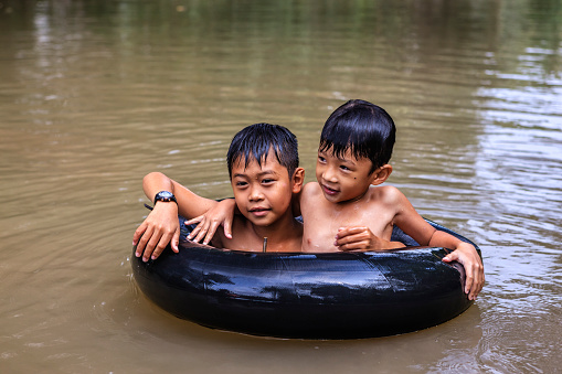 Two little Vietnamese boys having fun in Mekong River Delta, Vietnam