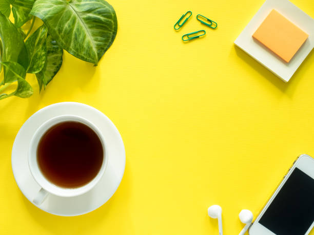 istock Green leaves plant coffee Cup on yellow desktop, flat lay, copy space. 952782578