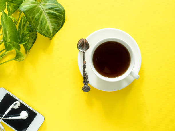 istock Green leaves plant coffee Cup on yellow desktop, flat lay, copy space. 952782898