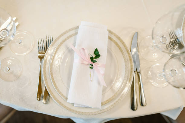 istock Serving, setting table. Two plates and silverware cutlery  linen napkin are decorated with pink ribbons and branch greens. Wedding table decoration. Artwork. flat lay. top view. Close up. 952786586