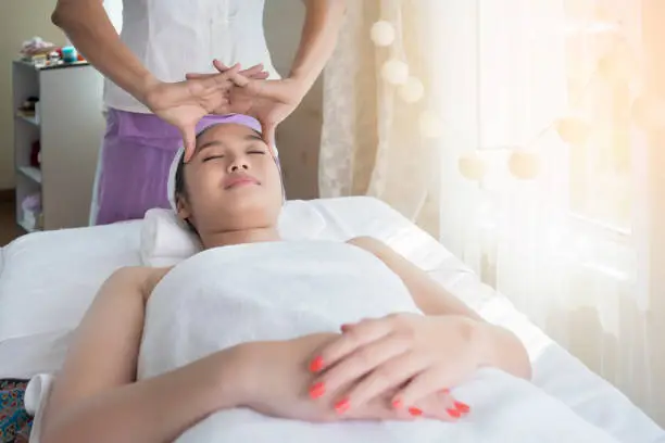 Photo of Beautiful young Asian woman relaxing , lying on massage table and having Thai traditional massage in spa salon