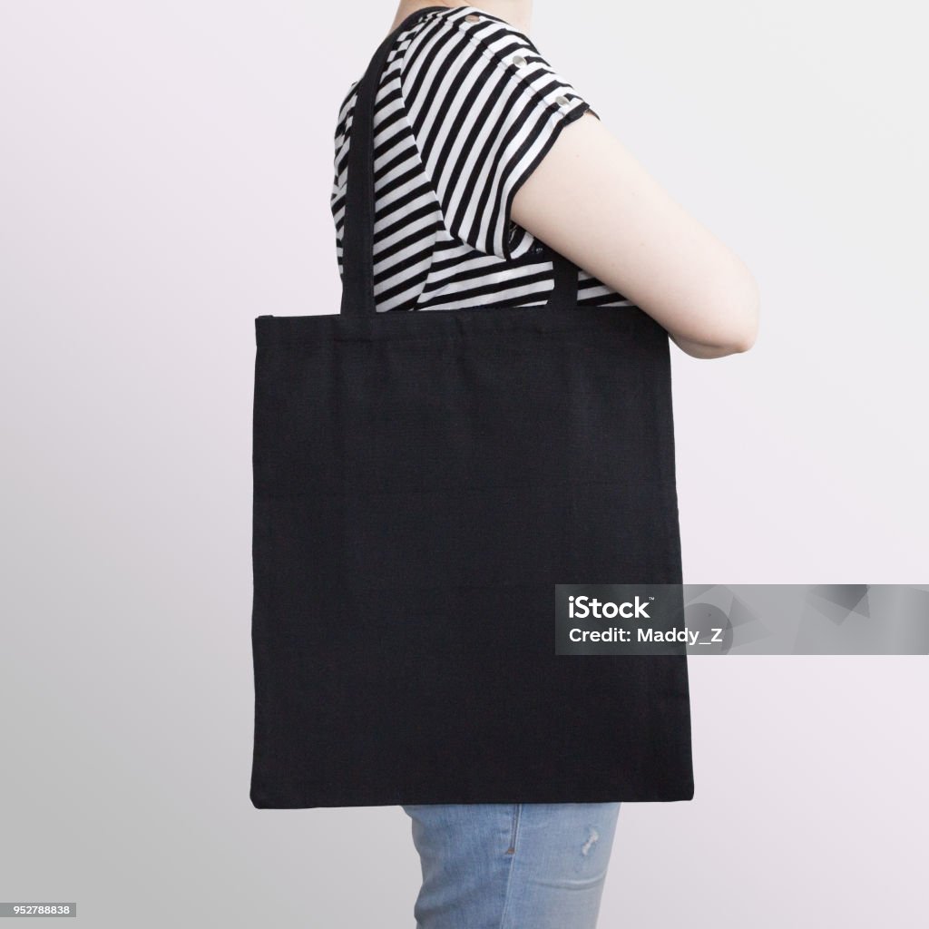 Girl is holding black cotton eco tote bag, design mockup. Girl is holding black cotton eco tote bag, design mockup. Handmade shopping bag for girls. Tote Bag Stock Photo