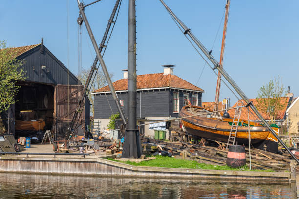 navires historiques au chantier naval avec cale de lancement dans le village néerlandais de workum - boathouse work tool equipment old photos et images de collection