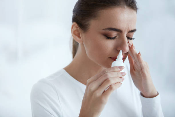 Cold. Beautiful Woman Using Nasal Spray Cold. Portrait Of Beautiful Young Woman Sniffing Nasal Spray Closing One Nostril. Closeup Of Female Feeling Sick With Running Nose Using Sinus Medication For Blocked Nose. Healthcare. High Resolution nasal spray stock pictures, royalty-free photos & images